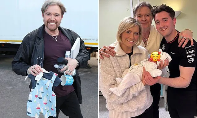 New grandfather Darren Day proudly shows off a babygrow