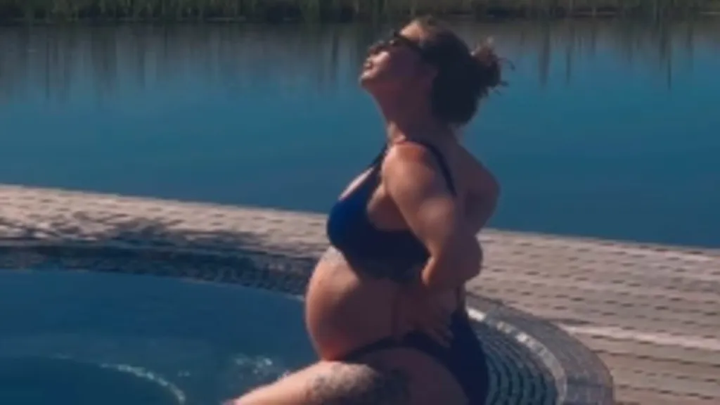 Olivia Bowen displays her baby bump in a navy bikini amid babymoon